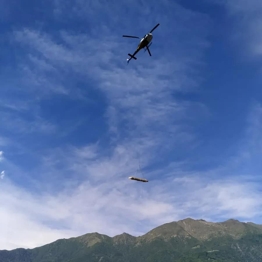 villa in legno moderna sul lago maccagno, elicottero che trasporta le pareti